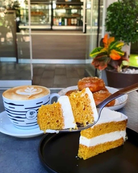 Carrot cake and a cappuccino by the pastry counter.